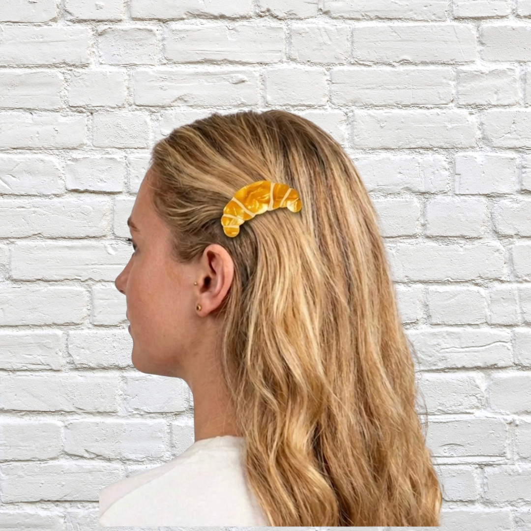 Gelbe Croissant-Haarspange von Eat My Socks im blonden Haar