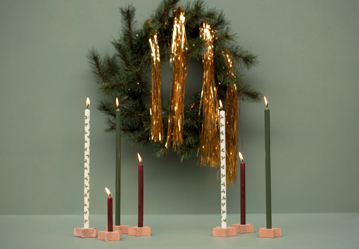 Holly Jolly Kerzen in kleinen Holzhaltern vor einem Weihnachtskranz