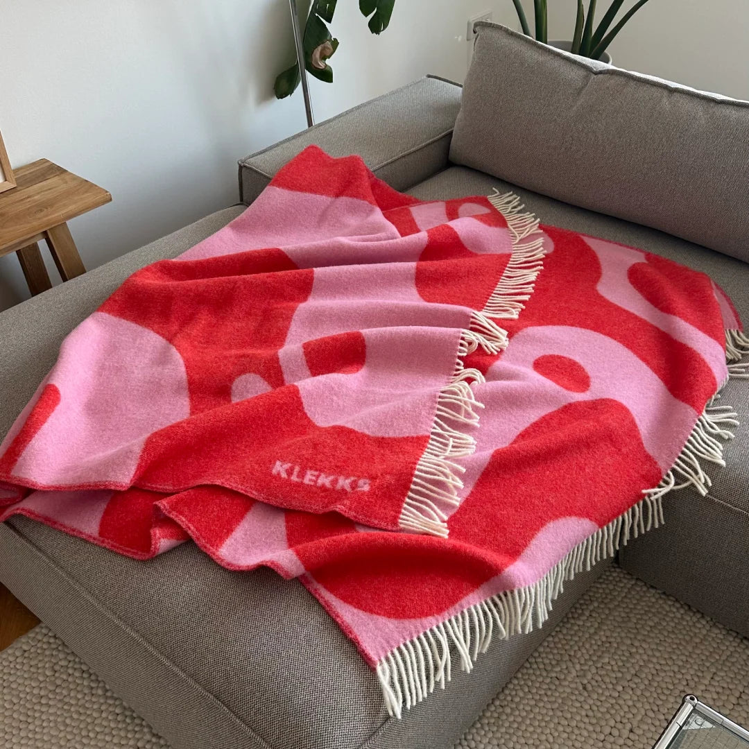 Pink-rote Klekks Decke No. 8 auf einem grauen Sofa