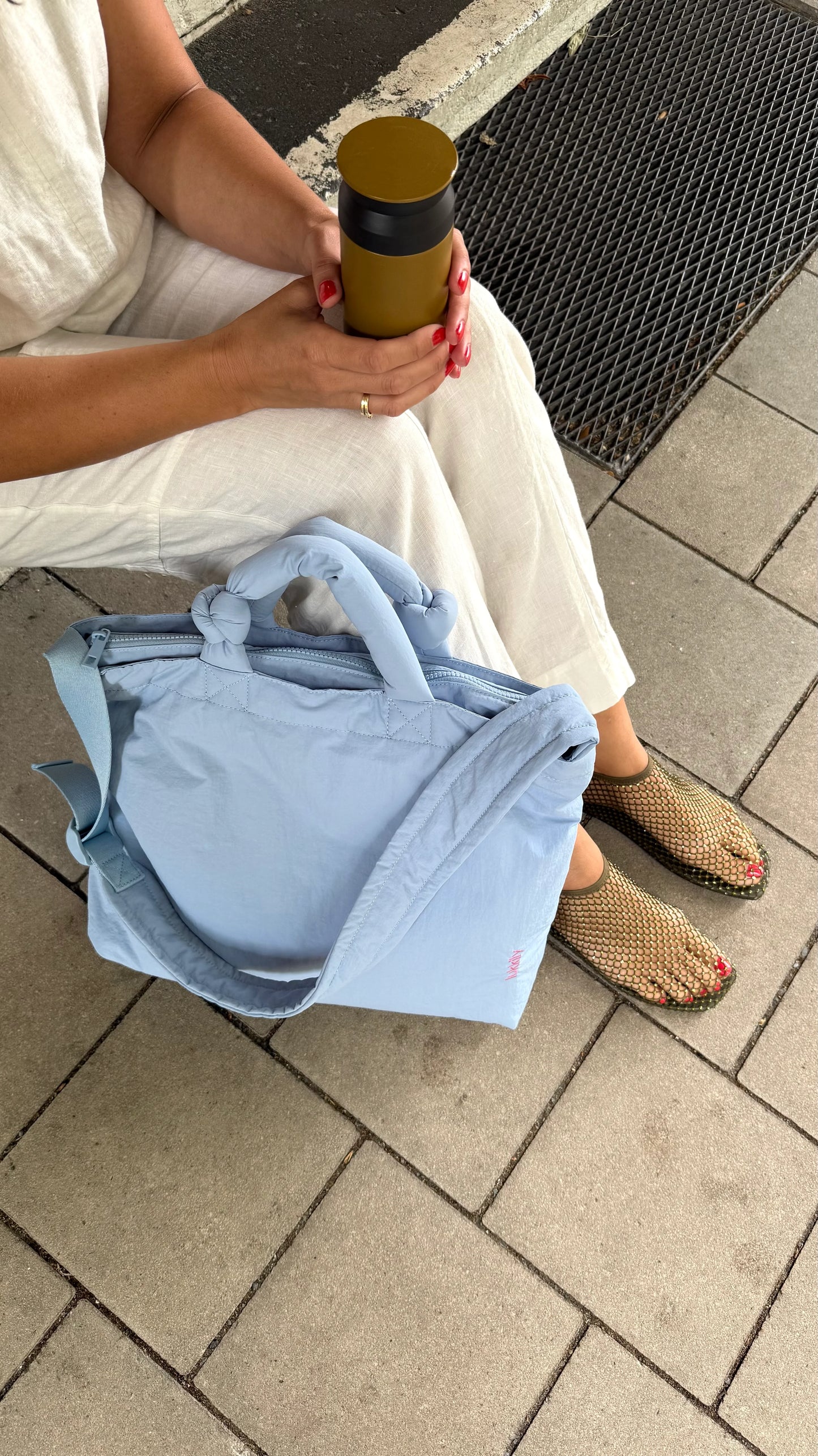 Hellblaue Lukkily Tote Bag neben einer sitzenden Frau