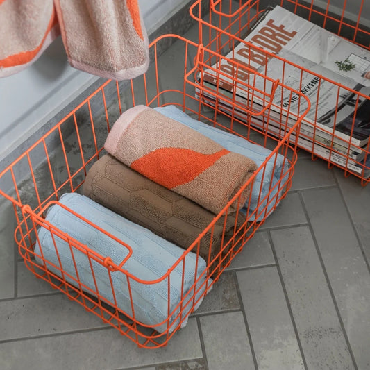 Orangefarbener Metallkorb „Wire Basket Medium“ von Mette Ditmer zur Aufbewahrung von Textilien.