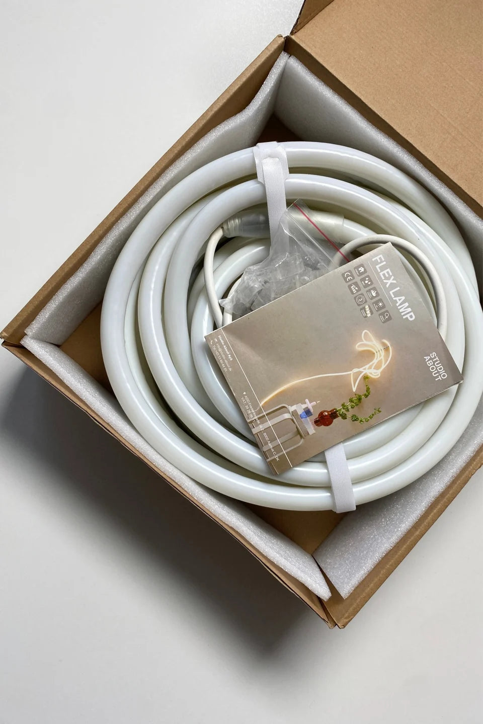 Aufgerollte FLEX TUBE mit Zubehör in der Produktverpackung